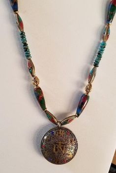 Turquoise and Agate Composite Necklace with Brass East Indian Pendant and Brace Spacers with Inlaid Turquoise and Coral Southwestern meets East Indian style necklace with Turquoise roundels and agate composite stones and East Indian round pendant.   Really cool and stylish necklace with an East Indian/Southwestern vibe!  With the variety of shapes, textures and colors in this piece, it certainly adds interest and uniqueness.  The agate composite stones are multicolored with reds, greens, golds and blues.  The brass components add a gold pop of color.   The turquoise colored patina of the toggle clasp blends right in with the total look.  What an eye catcher - and certainly to garner many compliments to the wearer! Indian Pendant, Brass Components, Turquoise And Coral, Stylish Necklace, Necklace Turquoise, Castle Rock, Southwestern Style, Genuine Turquoise, Indian Style