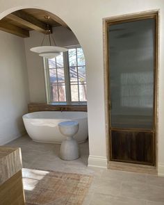 a bathroom with an oval bathtub next to a large window and wooden trim on the wall