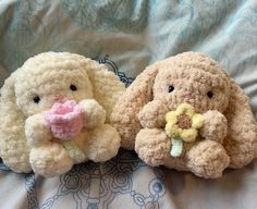 two stuffed animals sitting on top of a bed next to each other, one with a flower in it's mouth