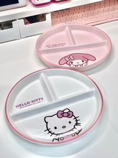 two hello kitty plates sitting on top of a desk