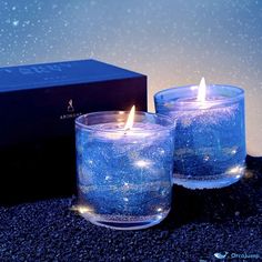 two blue candles sitting on top of a black table next to a box with stars in it