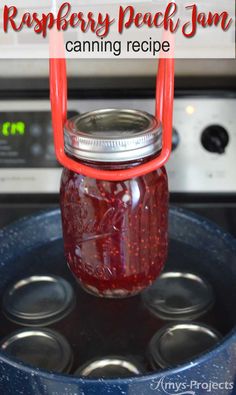 a mason jar filled with raspberry peach jam sitting on top of an oven