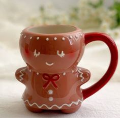 a ceramic mug with a red handle on a white surface