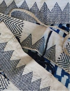 the blue and white fabric is laying on top of each other, with small triangles in it