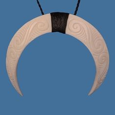 a white and black necklace hanging from a string on a blue background in the shape of a crescent