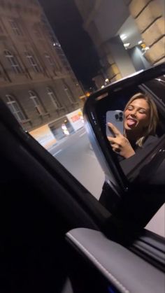 a woman taking a selfie in the side view mirror of a car at night