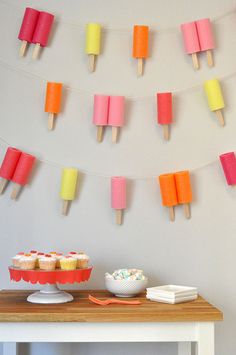 an ice cream sundae and cupcakes are displayed on a table with paper streamers