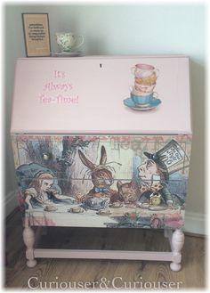 a pink chest with alice's tea party painted on the front and side panels