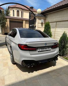 a white bmw car parked in front of a house with its trunk open and the door opened