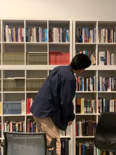 a man standing on top of a chair in front of a bookshelf