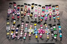 many different colored beads and key chains on a wooden floor with tags attached to them