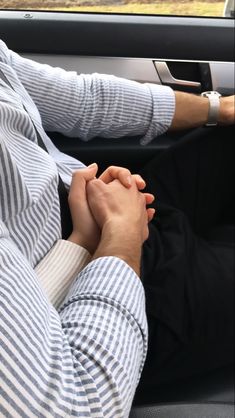 two people holding hands while sitting in a car