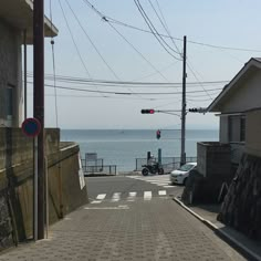 an empty street next to the ocean with power lines above