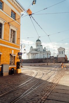 a train track running through the middle of a street next to a tall building with a dome on top