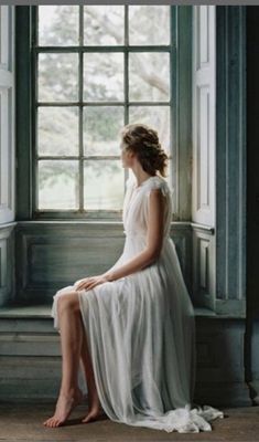 a woman sitting on a window sill looking out the window