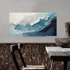 an abstract painting is displayed on the wall above a wooden table with a chair and vase