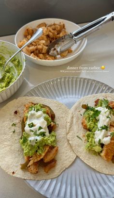 two fish tacos with guacamole and sour cream on top are sitting on a paper plate