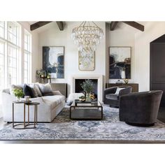 a living room filled with furniture and a chandelier hanging from the ceiling over a fire place