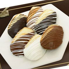 chocolate covered cookies on a white plate with a brown ribbon around it and a gift box in the background