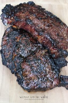 two pieces of meat sitting on top of a wooden cutting board