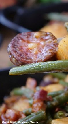 green beans, potatoes and bacon are being held by a spoon