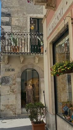 an old fashion store on the side of a building with flowers hanging from it's balconies