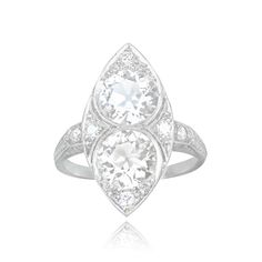 a white gold ring with two pear shaped diamonds on the sides and an oval diamond in the center