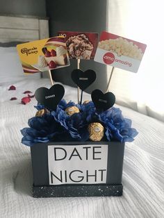 a black box filled with lots of chocolates on top of a white sheet covered bed