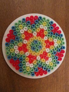 a white plate topped with lots of different colored buttons on top of a wooden table