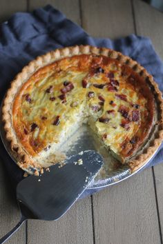 a pie sitting on top of a wooden table next to a spatula and knife