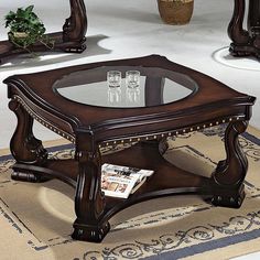 a wooden table with glass top on carpeted floor next to mirrors and vases