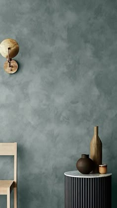 a chair and table in front of a gray wall