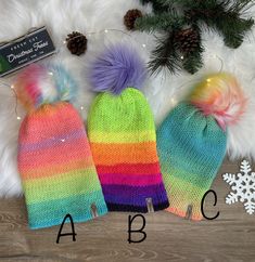 two knitted hats with pom poms on them