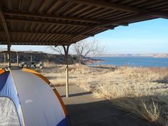 there is a tent that is pitched up on the ground next to some grass and water