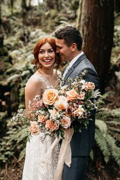 a bride and groom standing together in the woods holding bouquets with flowers on them