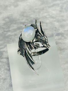 This ring is absolutely beautiful. High Detailed Dragon Ring With Prong Set Smooth Rainbow Moonstone Gemstone - Supplied With Gift Box. Ring is lovingly made of 925 Silver & Stamped 925 The beautiful Moonstone Cabochon Measures 13.6mm x 10.5mm and has a Beautiful Blue Flashes. The ring can adjusted from the back, but please be gentle when you adjust, so as not to damage the shape of the ring. The Dragon Design itself Measures 40mm tall x 24.8mm wide. Black Spinel Crystals have been used for the Silver Mystical Moonstone Ring For Jewelry Making, Mystical Moonstone Open Ring Jewelry, Silver Fantasy Jewelry For Formal Occasions, Mystical Cabochon Moonstone Ring Gift, Mystical Silver Gemstone Jewelry, Mystical Silver Moonstone Ring Gift, Mystical Gemstone Jewelry For Formal Occasions, Cabochon Open Ring Jewelry Gift, Adjustable Silver Moonstone Jewelry