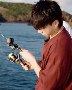 a young boy holding a fishing rod and spinning it