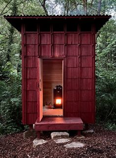 an outhouse in the woods is lit up with a small fire place inside it