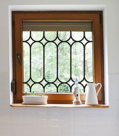 a kitchen window with pots and cups on the ledge