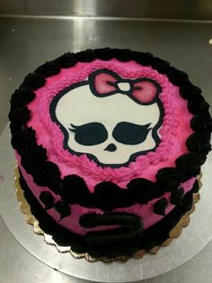 a cake decorated with pink and black icing has a skull in the middle on it