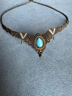 a necklace with blue stone and gold beads on a gray background, close - up