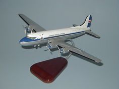 a model airplane flying in the sky with a wooden stand on it's side