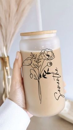 a person holding a glass with flowers on it and the words thank you written in black ink