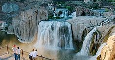 people are standing at the bottom of a waterfall