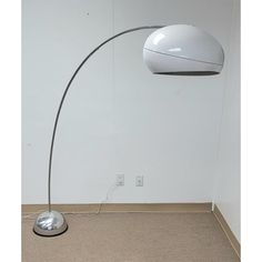 a lamp that is on top of a floor next to a wall with a light in it