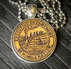 a necklace with a coin on it sitting on top of a wooden table next to a chain