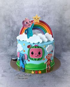 a birthday cake decorated with cartoon characters and rainbows