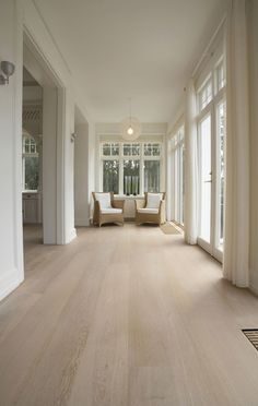 an empty living room with white furniture and large windows on both sides of the room