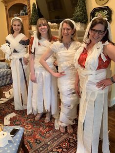 four women dressed up in white dresses standing next to each other