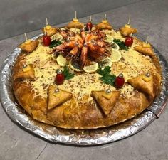 a large pizza covered in lots of toppings on top of tin foil and topped with fruit